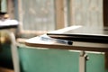 A photo of a cream colored wooden table on which there is a laptop and a blue ballpoint pen