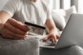 Photo cropped of caucasian guy 30s in casual jeans using notebook and holding credit card for online shopping, while sitting on s