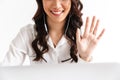 Photo cropped of cheerful asian woman 20s wearing office clothing and earphones waving at laptop, during video call or online con