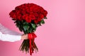 Photo of cropped man arms hold big one hundred red bright roses bunch giving girlfriend surprise hiding face secret