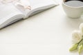 Photo of cup of coffee white flowers and glasses on open book on white table with copyspace Royalty Free Stock Photo