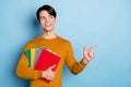 Photo of curious brunet millennial guy hold books look empty space wear brown sweater isolated on blue color background