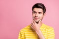 Photo of curious brunet young man look empty space wear yellow t-shirt isolated on pink color background