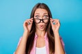 Photo of curious shocked young lady take off eyeglasses open mouth wear pink striped shirt isolated blue background