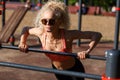 Photo curly blonde sports pulls up on sports simulator in park