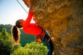 Photo of curly-haired female tourist clambering over rock Royalty Free Stock Photo