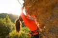 Photo of curly-haired female tourist clambering over rock Royalty Free Stock Photo