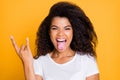 Photo of curly wavy excited crazy screaming girl sticking tongue out with horned fingers rock sign screaming isolated in Royalty Free Stock Photo