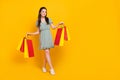 Photo of cute adorable lady dressed green dress walking holding shoppers empty space isolated yellow color background Royalty Free Stock Photo