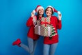 Photo of cute adorable women santa elves wear ornament pullovers packing x-mas gifts isolated blue color background