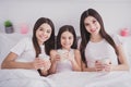 Photo of cute beautiful three sisters sleepwear sitting bed having rest drinking morning beverages inside indoors home