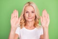 Photo of cute blond elder lady show stop sign wear white t-shirt isolated on pastel green color background