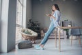 Photo of cute busy lady hold telephone talk raise palm crossed legs wear spectacles denim jeans footwear shirt in home