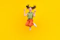 Photo of cute charming preteen girl dressed green top showing two v-signs jumping high smiling isolated yellow color