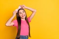 Photo of cute charming school girl wear pink t-shirt arms band looking empty space smiling isolated yellow color