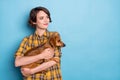 Photo of cute curious girl pet owner cuddle dachshund look empty space wear plaid shirt isolated blue color background