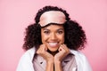 Photo of cute dreamy curly dark skin woman dotted nightwear smiling rolling white duvet arms cheeks isolated pink color
