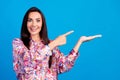 Photo of cute excited lady dressed print blouse looking pointing finger holding arm emtpy space isolated blue color Royalty Free Stock Photo