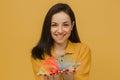 Photo of cute female with nice smile plays slinky. Wears yellow shirt, isolated yellow color background