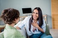 Photo of cute funny young ladies dressed shirts sitting couch smiling laughing indoors house room Royalty Free Stock Photo