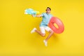 Photo of cute funny young man wear blue t-shirt dark glasses holding water circle shooting water gun isolated yellow