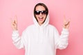 Photo of cute funny young woman dressed white sweatshirt glasses showing rock roll sign smiling isolated pink color Royalty Free Stock Photo