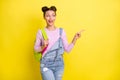 Photo of cute impressed young woman wear denim overall rucksack pointing empty space isolated yellow color background