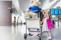 Portrait of cute little girl standing next to baggage cart in airport