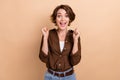 Photo of cute lucky lady wear brown shirt rising fists shouting yeah isolated beige color background