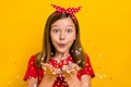 Photo of cute positive little teen woman blow send you confetti celebrate birthday isolated on yellow color background