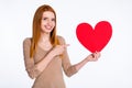 Photo of cute pretty redhair woman beige shirt pointing finger large red heart smiling empty space isolated white color