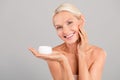 Photo of cute pretty senior lady nude shoulders applying face cream grey color background