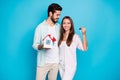 Photo of cute pretty young couple wear casual shirt holding small house keys isolated blue color background Royalty Free Stock Photo