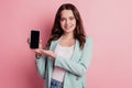 Photo of cute promoter lady hold phone hand presenting empty space touchscreen posing on pink background