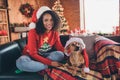 Photo of cute sweet dark skin lady wear red pullover smiling dressing small friend santa headwear indoors room home