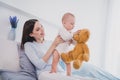 Photo of cute sweet small baby mommy wear blue shirt lying bed playing fluffy bear indoors home room Royalty Free Stock Photo