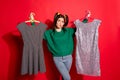 Photo of cute uncertain young woman dressed green knitted sweater try choose dress for date isolated red color