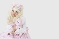 Portrait of cute woman dressed as a doll holding soft toy over gray background