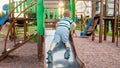 Photo of cute 3 years old toddler boy climbing and riding on big slide on children playground at park Royalty Free Stock Photo