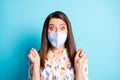 Photo of cute young girl with raised fists wearing blue respiratory mask isolated on pastel blue color background