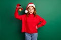 Photo of cute young lady hold demonstrate three baubles wear red sweater x-mas cap jeans isolated green color background