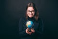 Photo of cute young woman holding globe and smiling over dark background Royalty Free Stock Photo