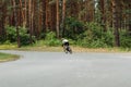 Photo of a cyclist athlete in motion on a workout, riding on an asphalt forest road, rear view Royalty Free Stock Photo