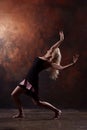 Photo of dancing blonde girl looking back in black dress on brown background Royalty Free Stock Photo