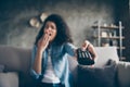 Photo of dark skin wavy lady homey mood holding tv remote control sleepy boredom yawning turn television off sitting Royalty Free Stock Photo