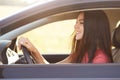 Photo of delighted glad brunette female driver looks happily at windscreen, holds hands on wheel, drives fast automobile, admires Royalty Free Stock Photo