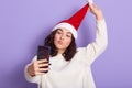 Photo of delighted peaceful young curly haired girl closing her eyes, feeling smell of coffee from thermal cup, enjoying hot drink Royalty Free Stock Photo