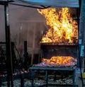 Photo depicting people making a grilled meat immersed in smoke. fire and coals.