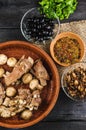 Stewed champignons and beef ribs with onions in a glossy plate, spices, parsley, dill. on a black wood Royalty Free Stock Photo