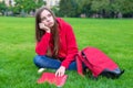 Photo of depressed passive sad teen girl sitting on green grass lawn is not willing to do home task looking away leaning on hand Royalty Free Stock Photo